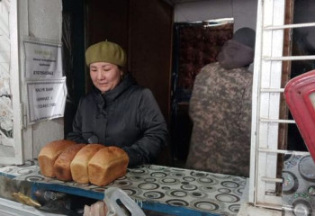 Участковый инспектор полиции раздает бесплатный хлеб в Костанайской области